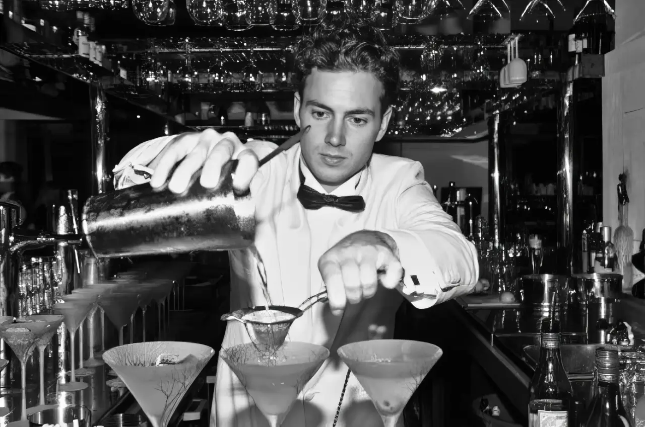 A bartender straining martinis