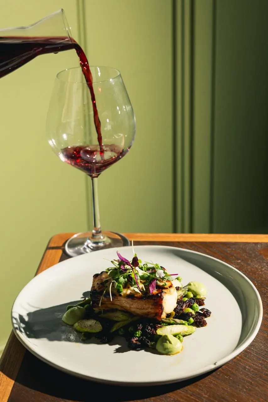 Red wine poured beside a fish entree