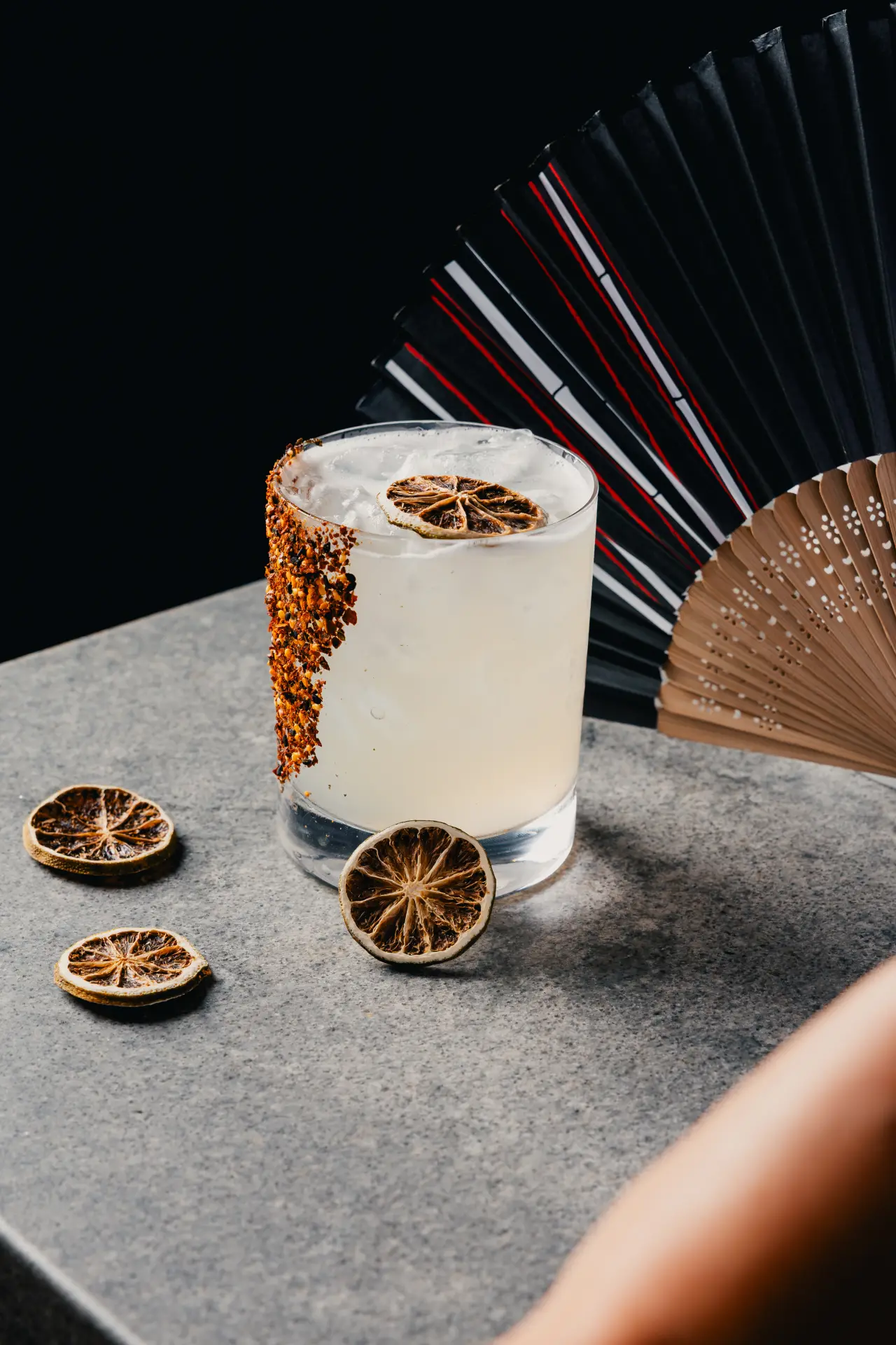 A craft cocktail with a chili salt rim and dried citrus