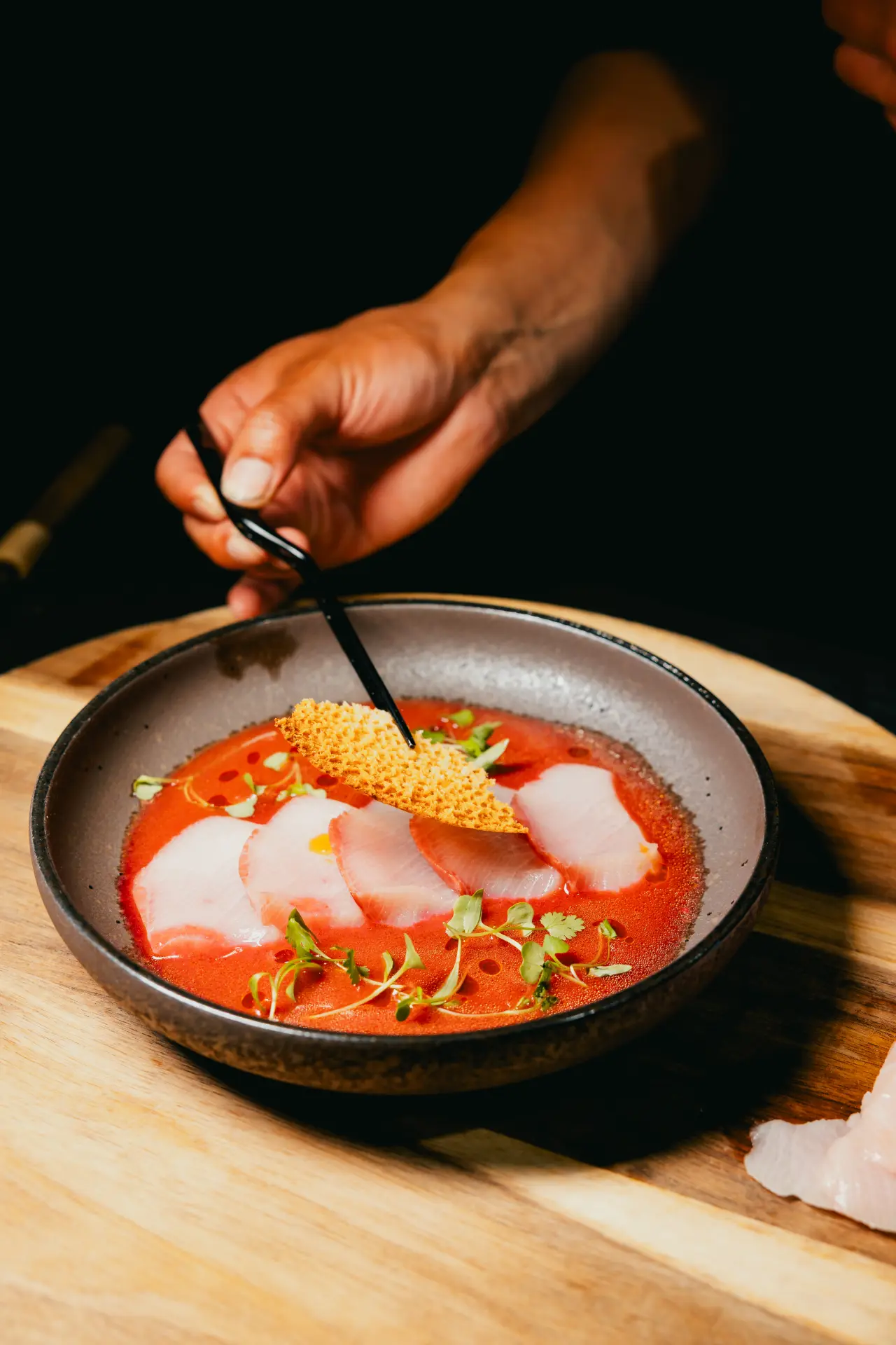 A chef plating yellowtail crudo at KUZA