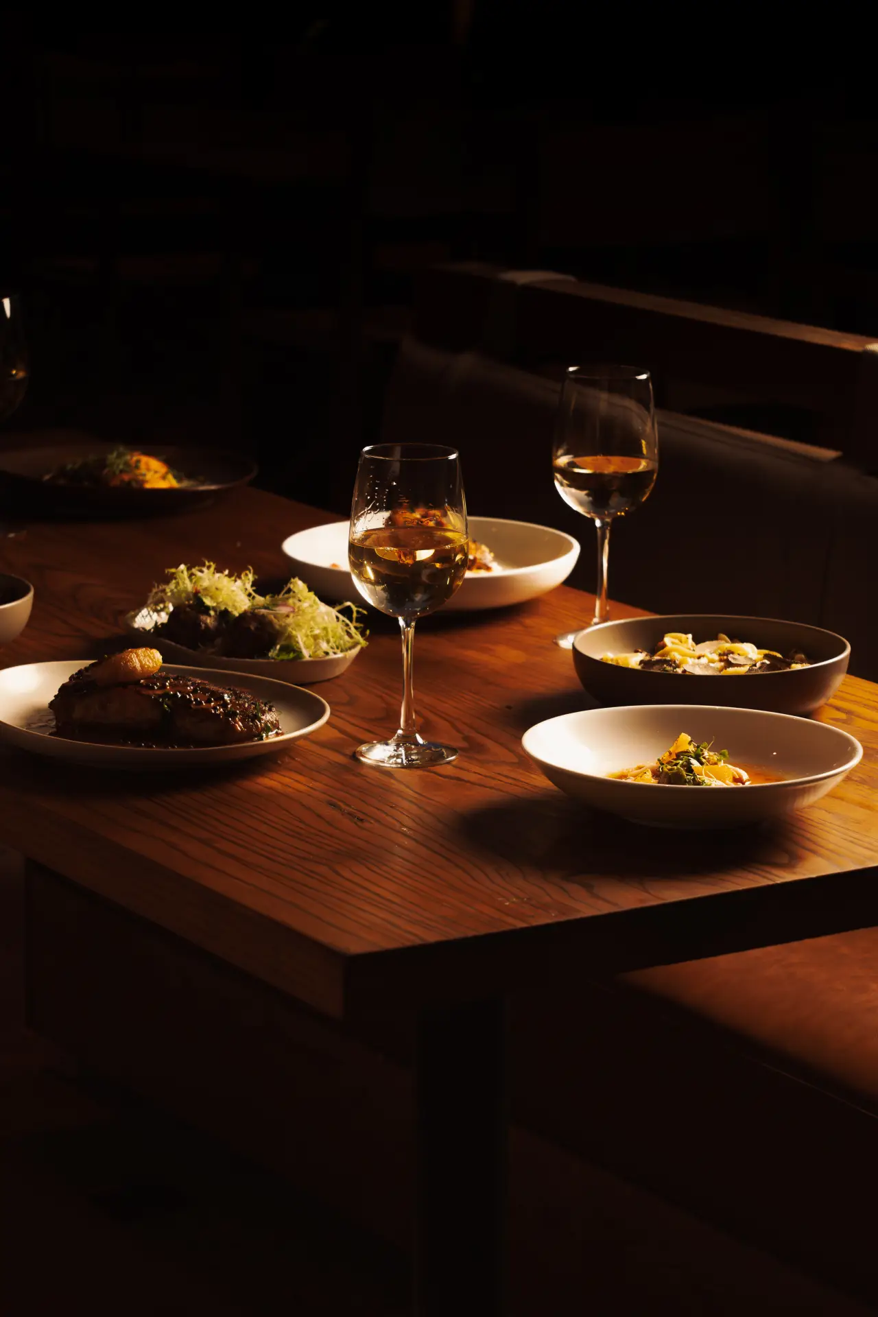 A dinner table set with plates and white wine