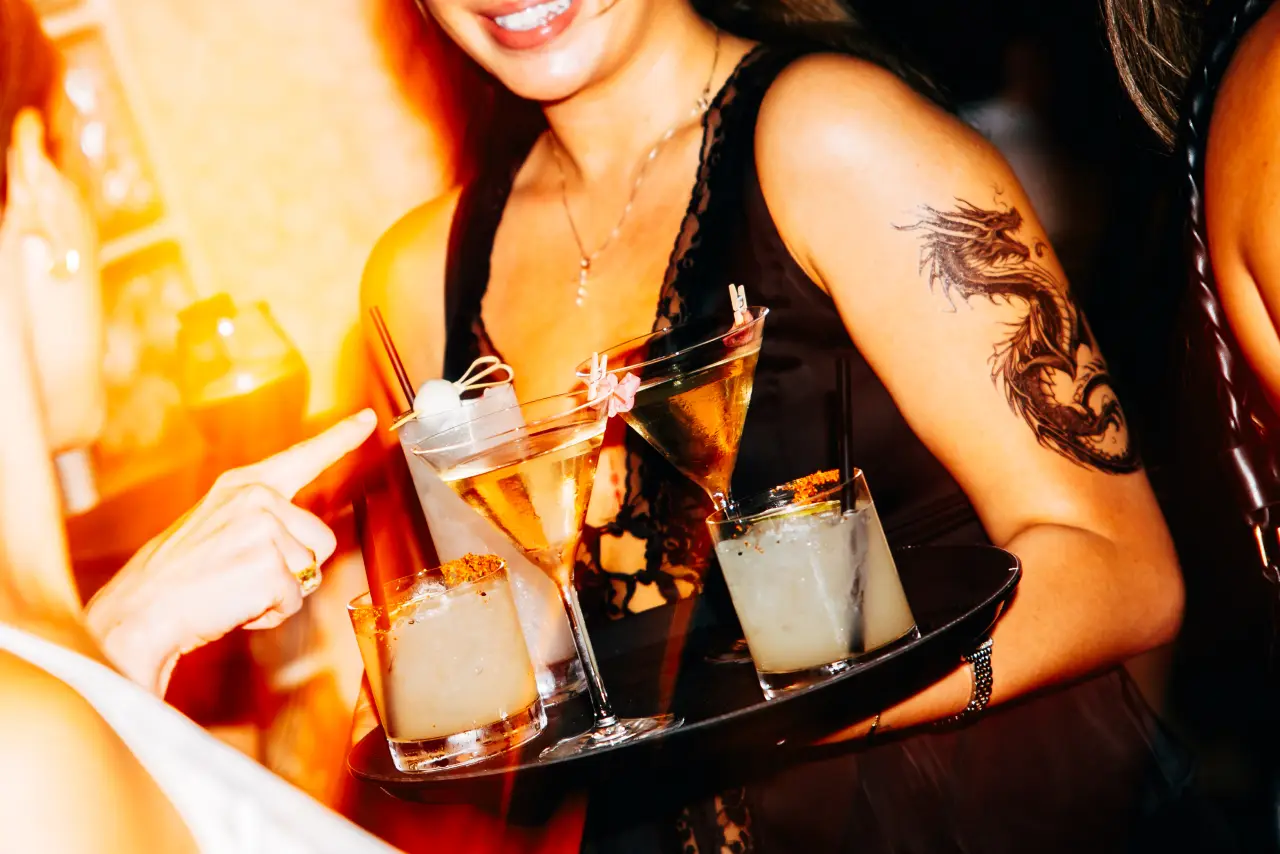 A server carrying a tray of cocktails at KUZA