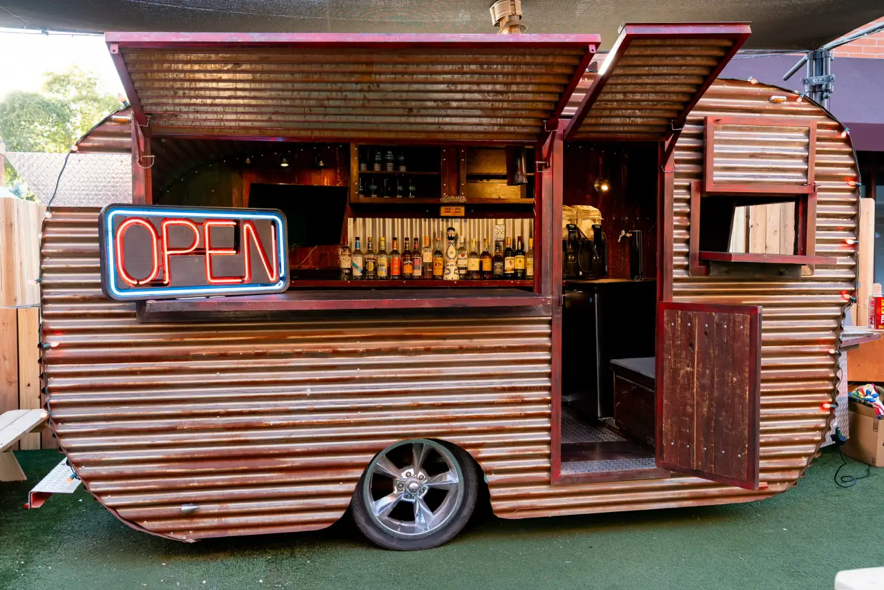 The vintage trailer bar behind Neon Spur with its OPEN sign lit